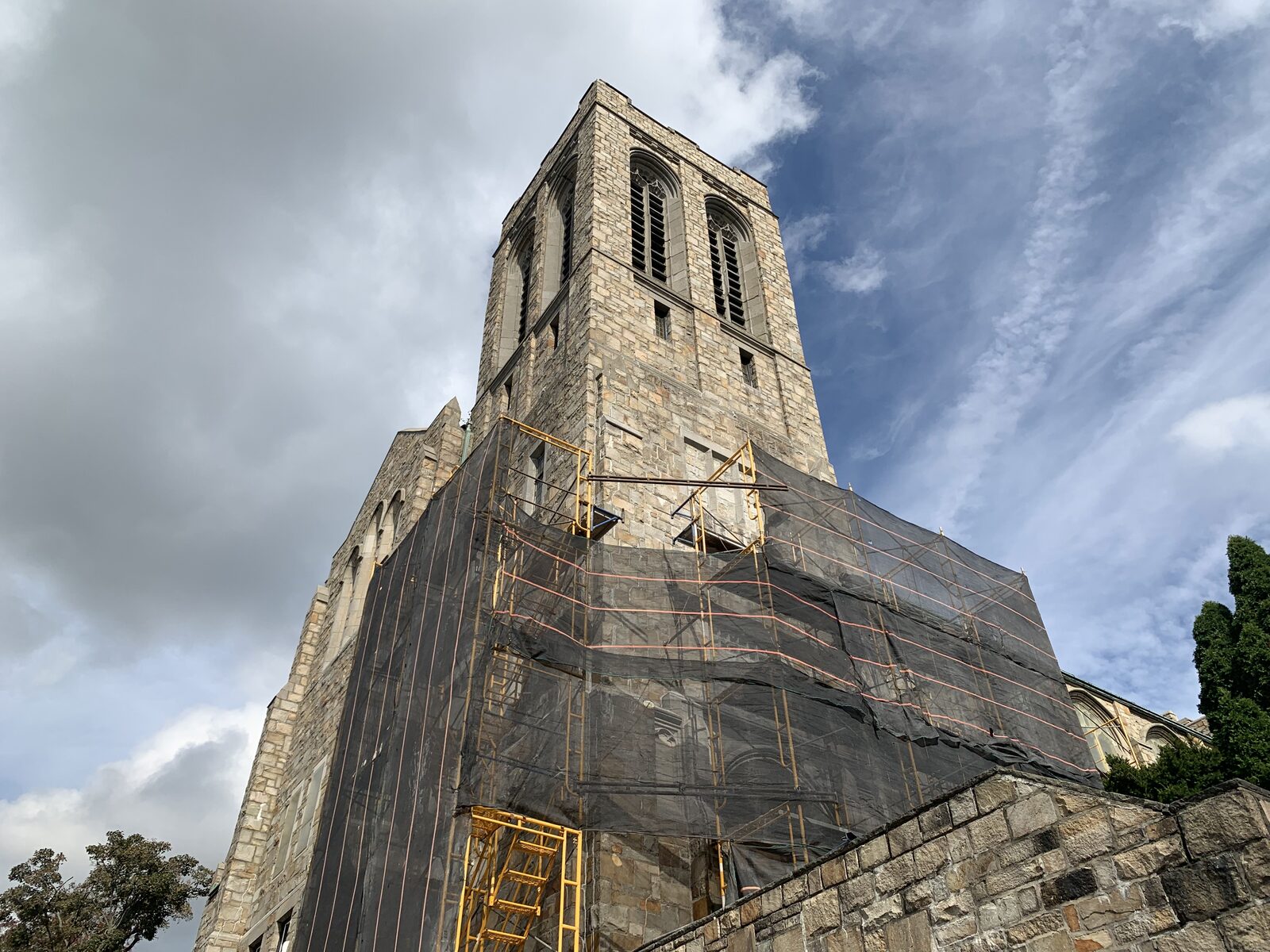 Wide view of the historic stone tower with scaffolding and protective netting